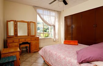 A bedroom with a bed, dresser, and mirror